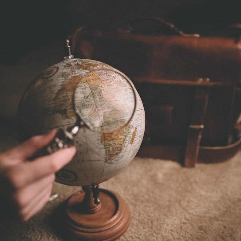 Stop living small - globe with magnifying glass